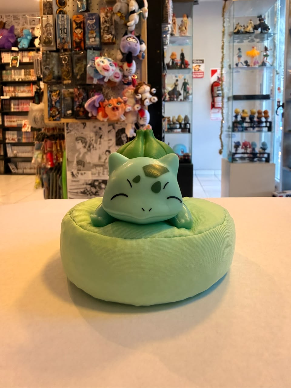 FIGURA GASHAPON DE BULBASAUR DURMIENDO SOBRE COJIN VERDE