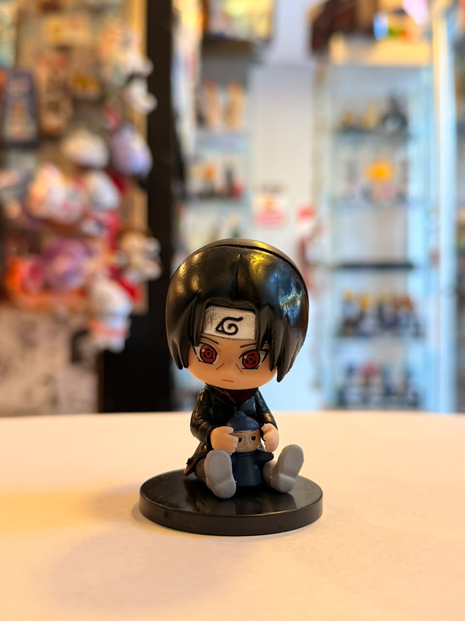 FIGURA GASHAPON DE ITACHI SENTADO SOSTENIENDO MUÑECO