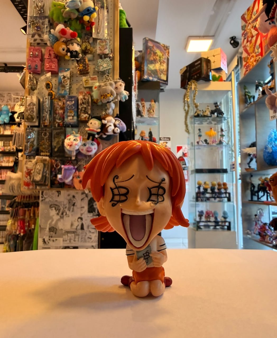 FIGURA CABEZON DE NAMI SENTADA, ABRIENDO LA BOCA Y SOSTENIENDO LIBRO