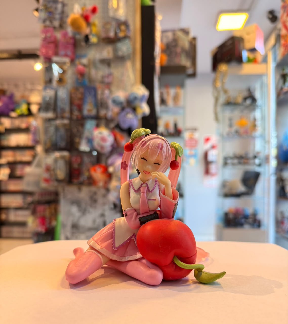 FIGURA DE SAKURA MIKU SENTADA SOBRE UN COJIN DE CEREZA